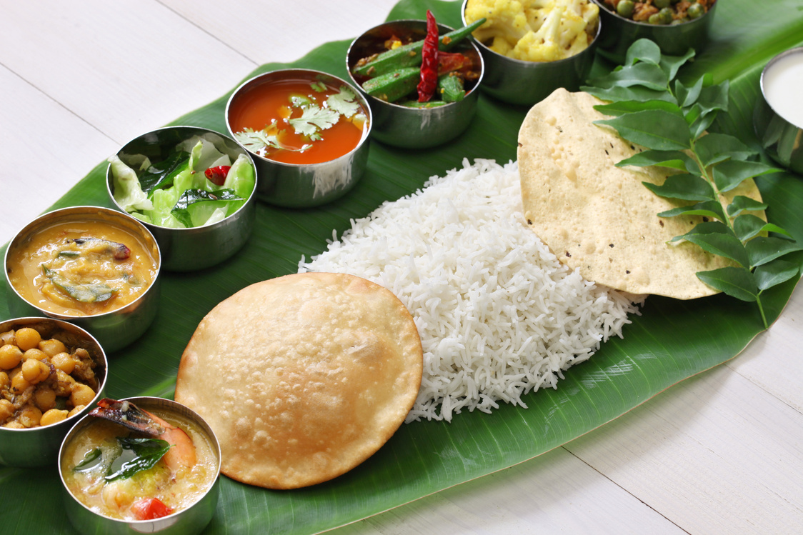 A South Indian traditional with Rice and various types of sides are arranged on a banana leaf